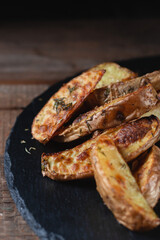 Delicious baked country potatoes on a slate cutting stone on a wooden table