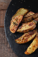 Delicious baked country potatoes on a slate cutting stone on a wooden table