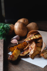 Delicious baked country potatoes with spices, dill and green onions, on a wooden table