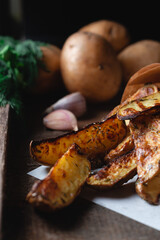 Delicious baked country potatoes with spices, dill and green onions, on a wooden table