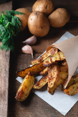 Delicious baked country potatoes with spices, dill and green onions, on a wooden table