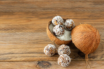 Healthy food concept. Homemade coconut energy balls in cocnut shell on wooden background.