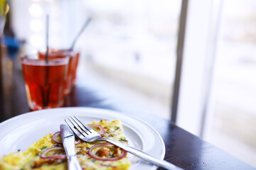A glass of drink tropical fruits soda and seafood pizza on wooden table in the cafe.