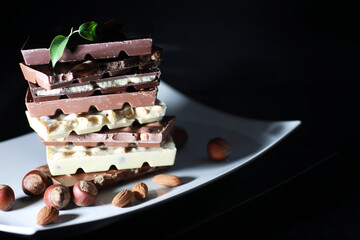 A bar of milk chocolate. Homemade milk chocolate with almonds and dried strawberries. Pieces of milk chocolate. Set of milk chocolate with tea.
