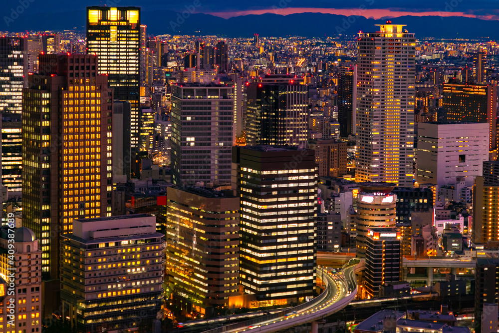 Canvas Prints Japan. Evening In Osaka. Light in the Windows of residential and office buildings. Evening in a Japanese city. A big city against a dark sky. Night city landscape. Travel to Japan.