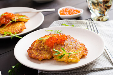 Fried potato pancakes with red caviar and sour cream, fritter, roesti. Traditional delicious food, lunch.