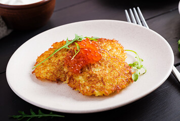 Fried potato pancakes with red caviar and sour cream, fritter, roesti. Traditional delicious food, lunch.