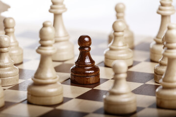 Black pawn standing among white chess figures