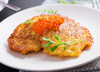 Fried potato pancakes with red caviar and sour cream, fritter, roesti. Traditional delicious food, lunch.