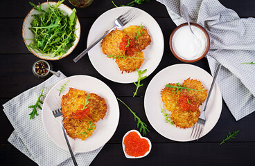 Fried potato pancakes with red caviar and sour cream, fritter, roesti. Traditional delicious food,...
