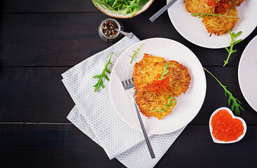 Fried potato pancakes with red caviar and sour cream, fritter, roesti. Traditional delicious food, lunch. Top view, flat lay