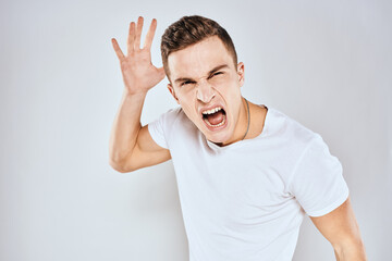 Emotional man gestures with his hands displeasure white t-shirt light background