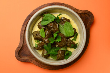 Piping hot baked cabbage rolls with sauce ready to serve. Traditional Georgian cuisine concept, over orange background.