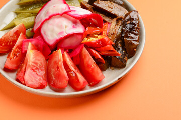 Preserved vegetables cut and served on a white plate. Pickled cucumbers, tomatoes, cabbage.