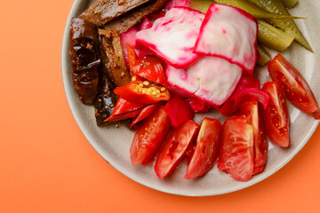 Preserved vegetables cut and served on a white plate. Pickled cucumbers, tomatoes, cabbage.