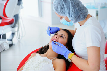 Young beautiful girl in dental office. Children's dentist examines teeth to a child.