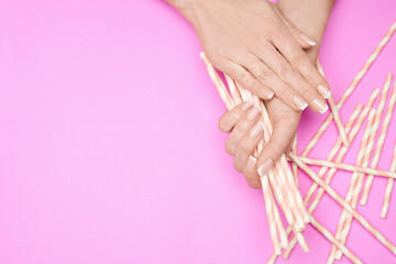 Beautiful Female Hands with French manicure over colorful paper background