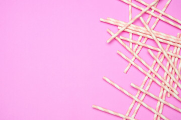 Flat lay with striped drink straws on pink background