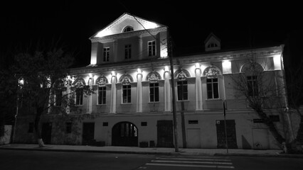 Fototapeta na wymiar The facade of the building at night under the light of street lamps
