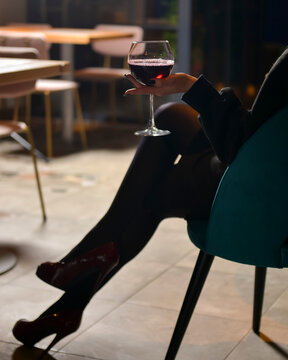 Beautiful girl legs and a glass of wine, attractive young girl drinking red wine.