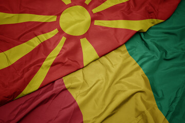 waving colorful flag of guinea and national flag of macedonia.