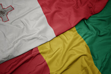 waving colorful flag of guinea and national flag of malta.