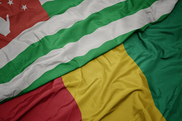 waving colorful flag of guinea and national flag of abkhazia.
