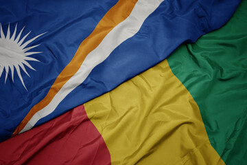 waving colorful flag of guinea and national flag of Marshall Islands .