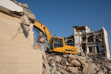 Crawler excavator working for the demolition of an old hotel. Excavator at construction side.
