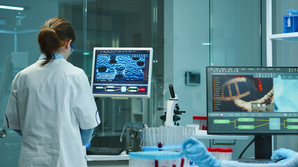 Scientist nurse typing medical reports on computer in scientific modern equipped laboratory....