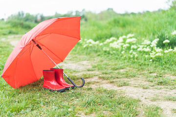 Boots and umbrella red on green grass in the field