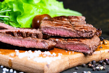 black angus steak with tomatoes, rosemary and lettuce on a board