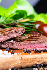 black angus steak with tomatoes, rosemary and lettuce on a board