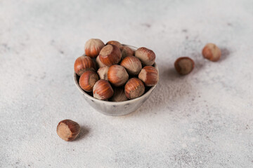 Pile of hazelnuts filbert in a bowl on a white background. Fresh nuts in their shells.