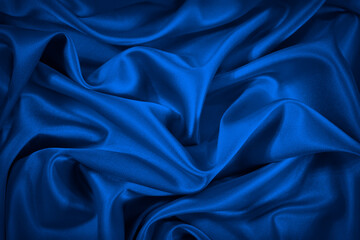 Deep blue silk satin fabric. Elegant abstract background. Liquid wave effect or silk with soft wavy...