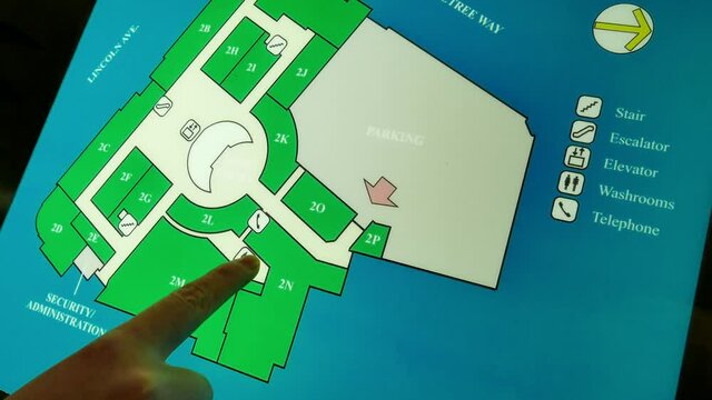 A woman checking washroom position in front of directory sign inside a shopping mall with 4k resolution