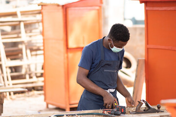 african carpenter at work wearing a face mask