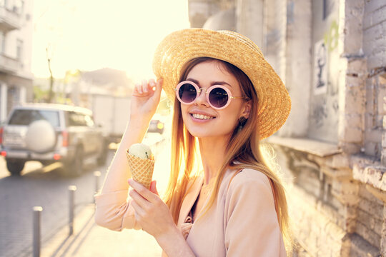 cheerful pretty woman in hat outdoors and ice cream walking in the city