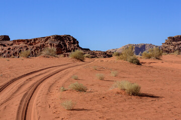 car tracks in the desert, beautiful relief mountains and clear blue sky, Wadi Rum desert, nature of Jordan