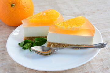 slices of orange cheesecake with a teaspoon on the beige tablecloth