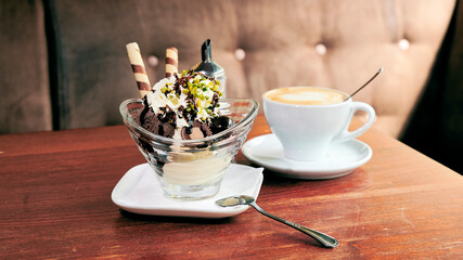 Schöner Becher mit Schokoladen Eis Waffeln und Soße  mit  Cappuccino in einem Eis Cafe