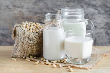 Closed up fresh organic soybean milk in glass bottle with fresh seeds on wooden background