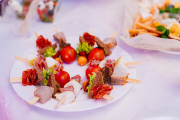 canapes of kebabs in a white plate on the table for the banquet. 