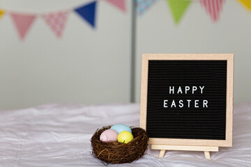 Stylish background with colorful easter eggs pastel colors in basket on bed. Easter celebrating at home during Coronavirus covid-19 pandemic