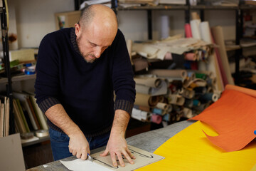 craftsman cutting leather with cutter  in workshop