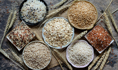 Top view of dry organic cereal and grain seeds consisted of barley, wheat, rice, and pearl barley seeds on sack fabric and grunge background in dark tone