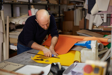 craftsman cutting leather with cutter  in workshop