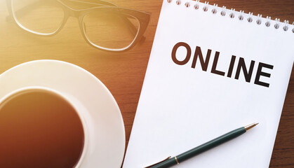 ONLINE - text on paper with cup of coffee and glasses on wooden background in sinlight.