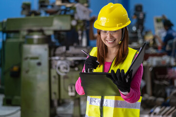 Portrait of Asian woman sales engineer checking the job list in paper over the photo blurred of lathe and milling machine background in metal factory, business industry with safety concept