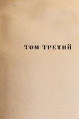 Page of an open old shabby yellowed book with blank sheets of vintage paper with the inscription in Russian Third volume